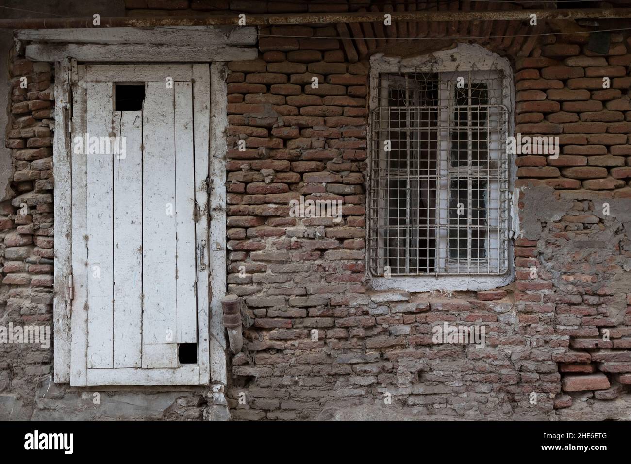 Vintage old wooden door and white window in an old red brick stone wall ...
