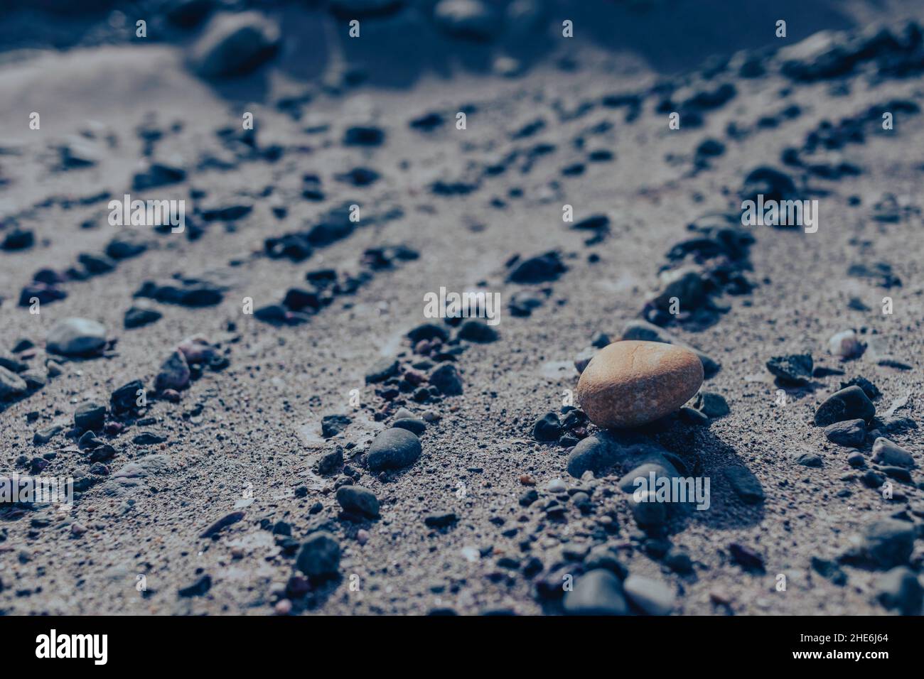 Sandy coast with many pebbles of different sizes at sunlight Stock