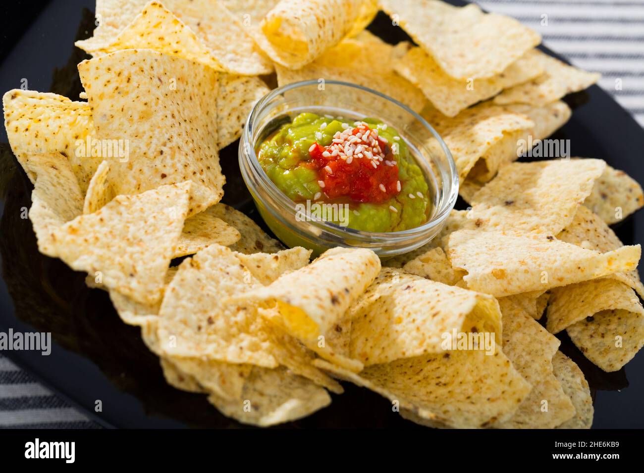 Nachos chips with sauces on black plate Stock Photo