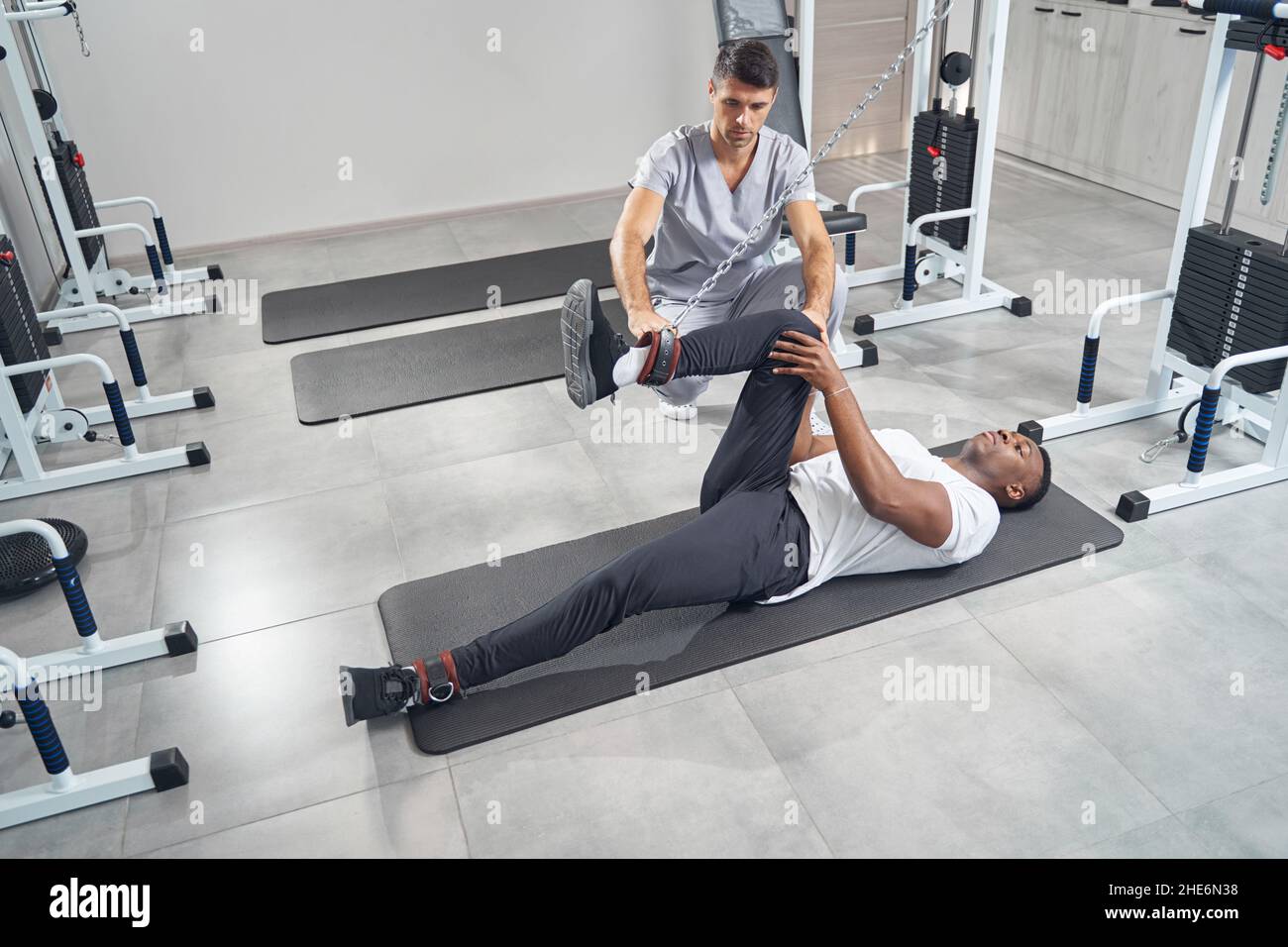 Male patient doing leg exercise using cable machine Stock Photo Alamy