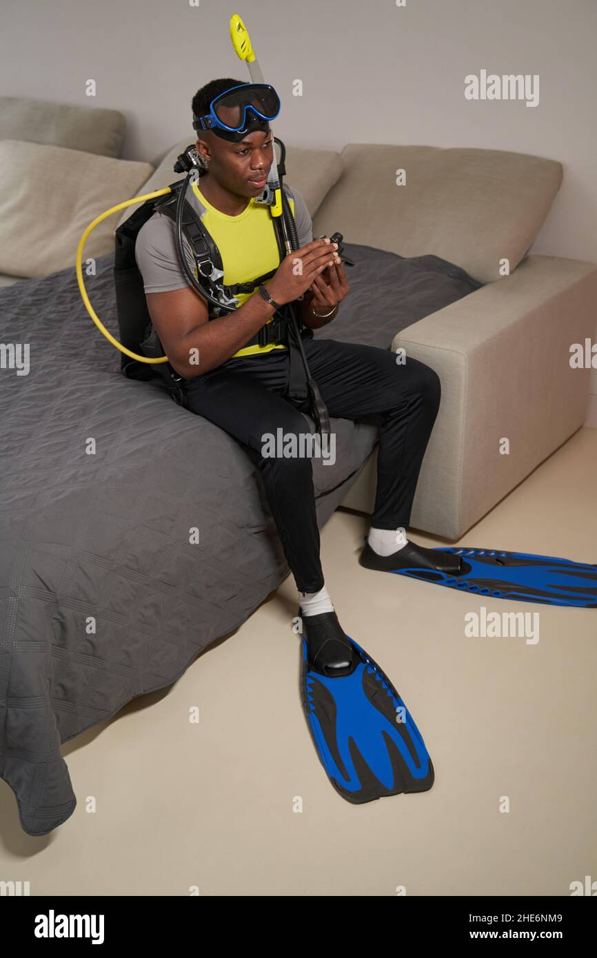 Multiracial man sitting on bed in scuba diving suit Stock Photo Alamy