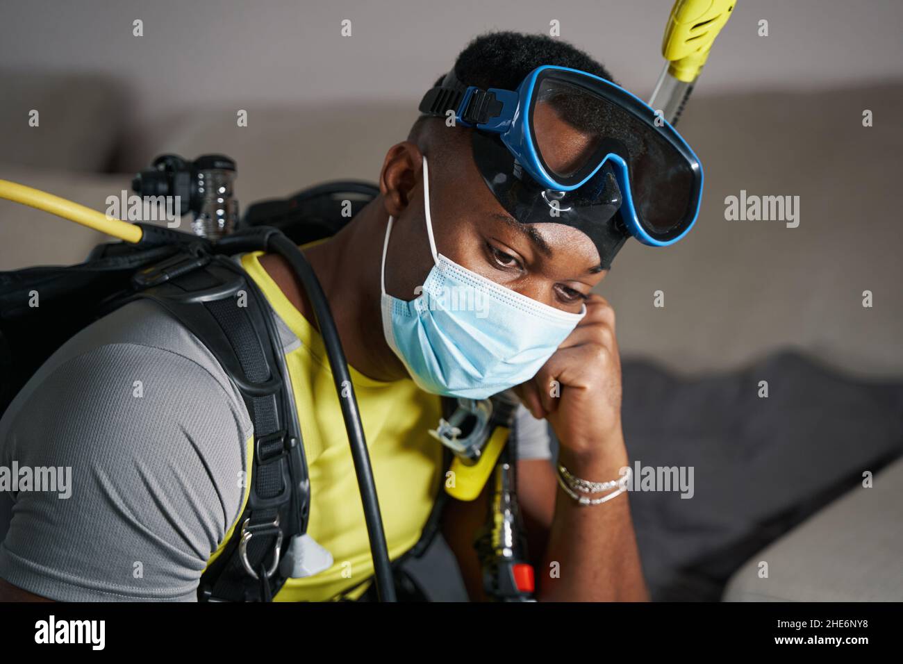 Depressed scuba diver sitting at home in gear Stock Photo