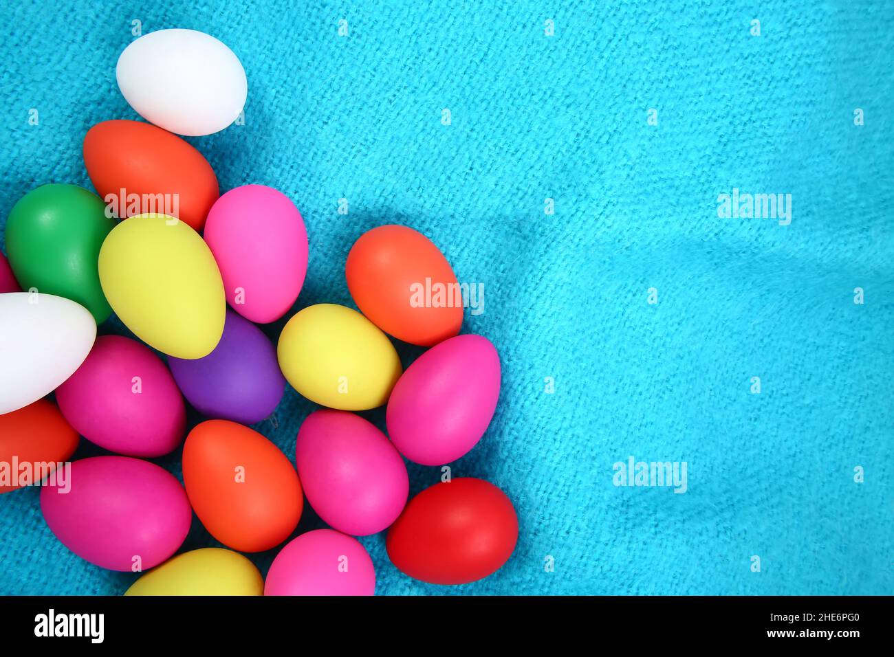 Multi colored painted easter eggs in pink, yellow, red, green, purple and white against a bright blue wool blanket background. Stock Photo