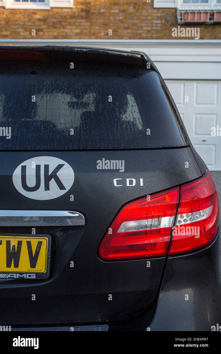 UK identifier car sticker on car. When travelling overseas motorists must now display the UK logo on the rear of their vehicle.UK Sticker on black ca Stock Photo