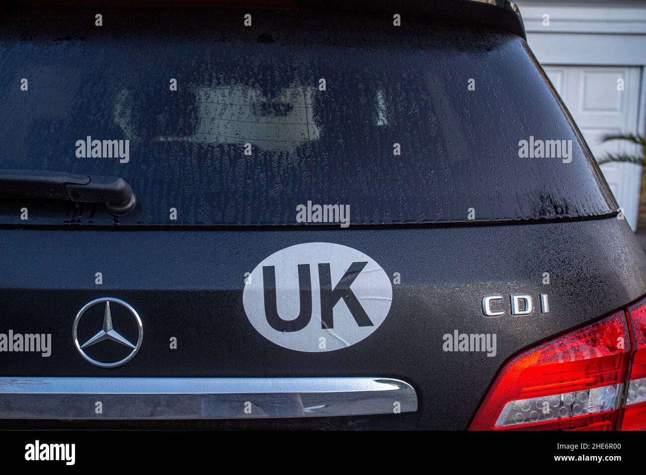 UK identifier car sticker on car. When travelling overseas motorists must now display the UK logo on the rear of their vehicle.UK Sticker on black ca Stock Photo