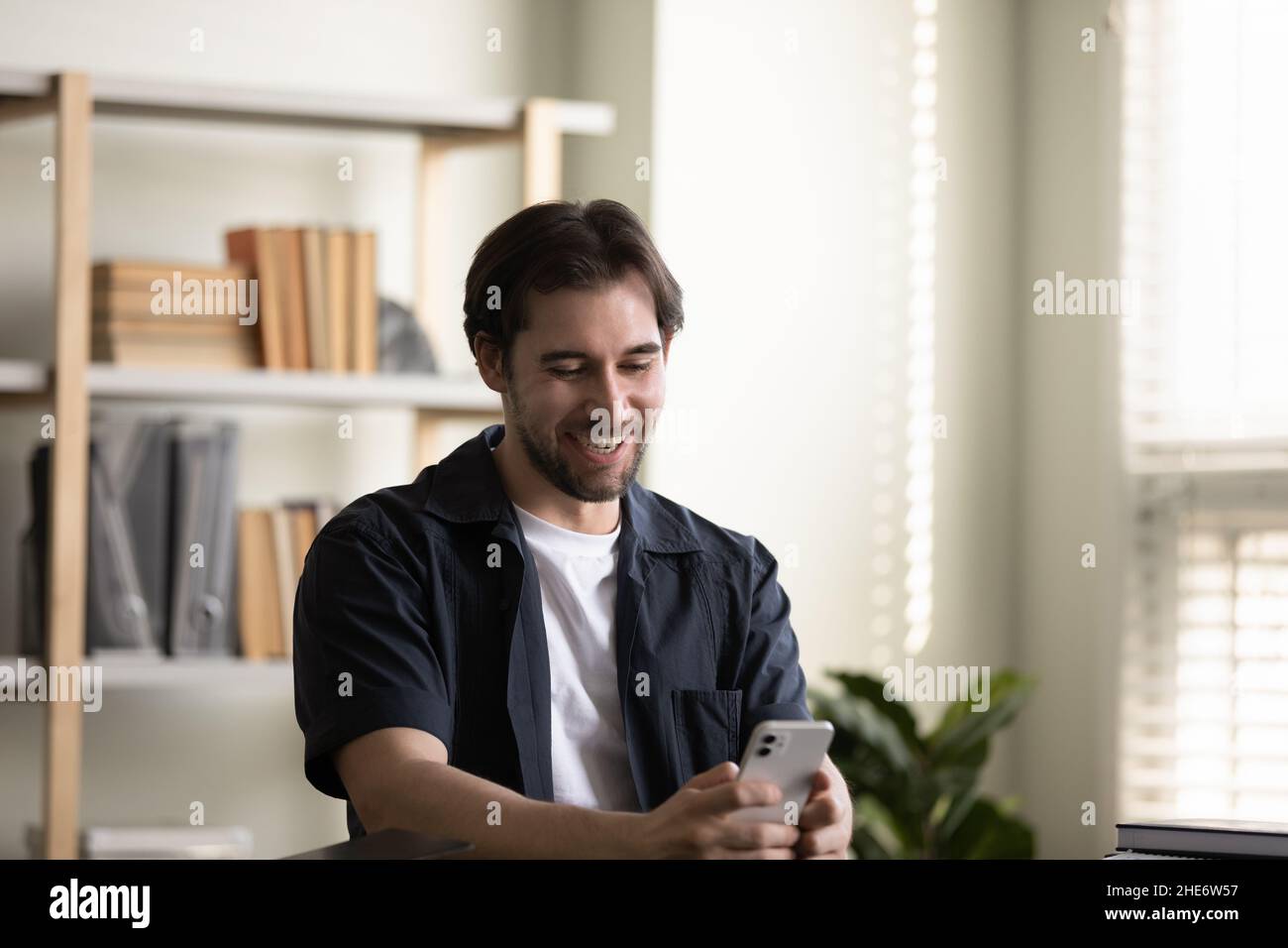 Happy millennial man using cellphone, tech addiction. Stock Photo