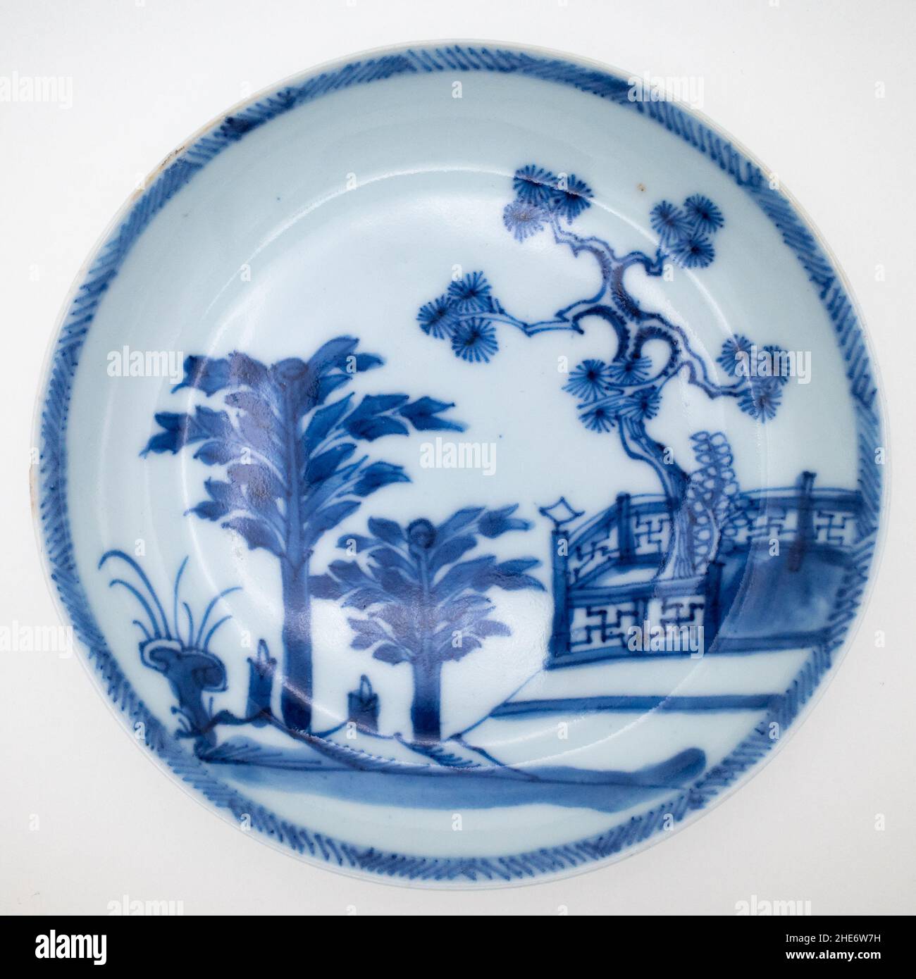 Antique Chinese 18th Century Blue and White Saucer Dish Wih a Scene Featuring Pine Tree Behind a Fence, Plantains and Lingzhi Fungus Stock Photo