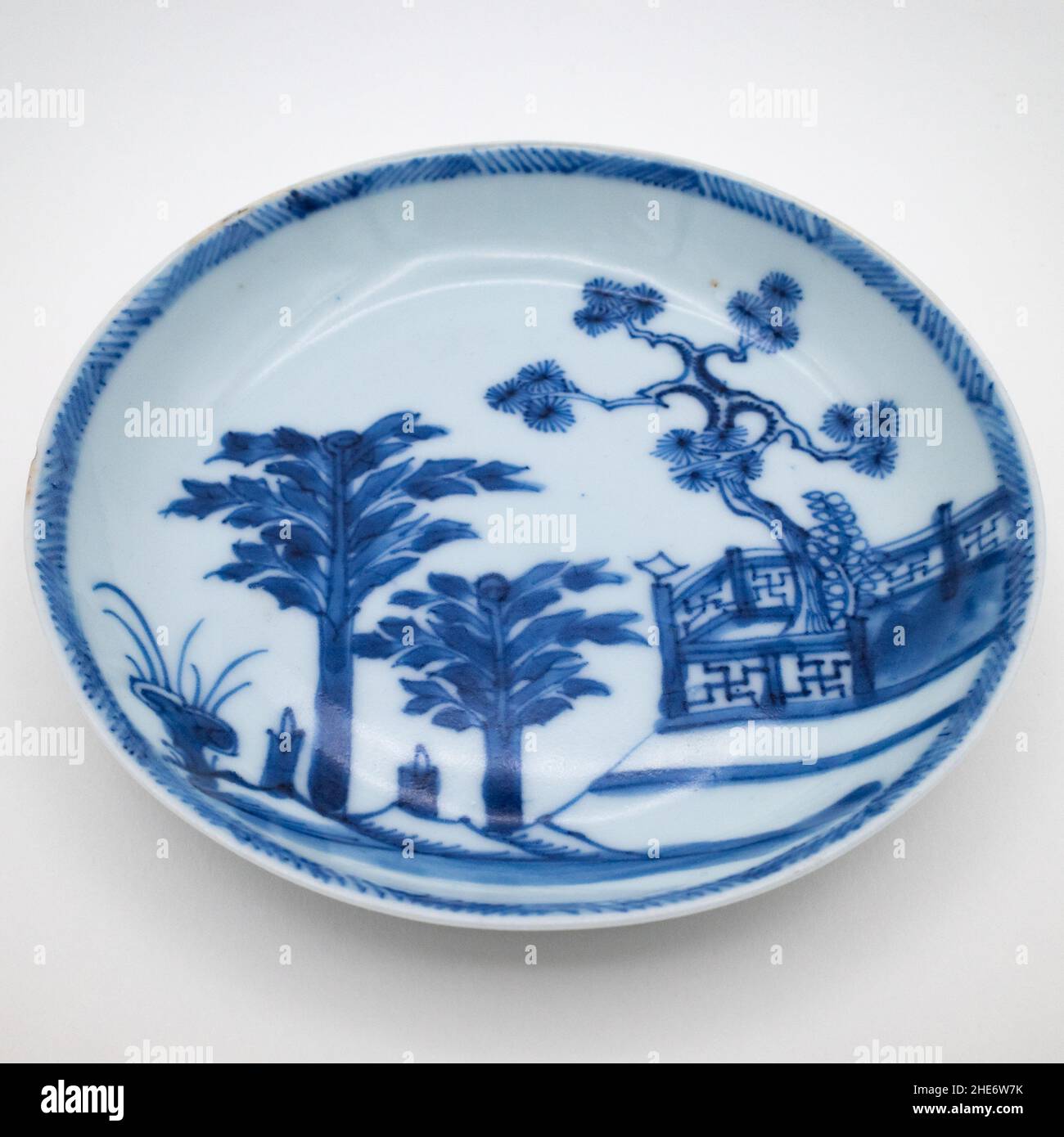 Antique Chinese 18th Century Blue and White Saucer Dish Wih a Scene Featuring Pine Tree Behind a Fence, Plantains and Lingzhi Fungus Stock Photo