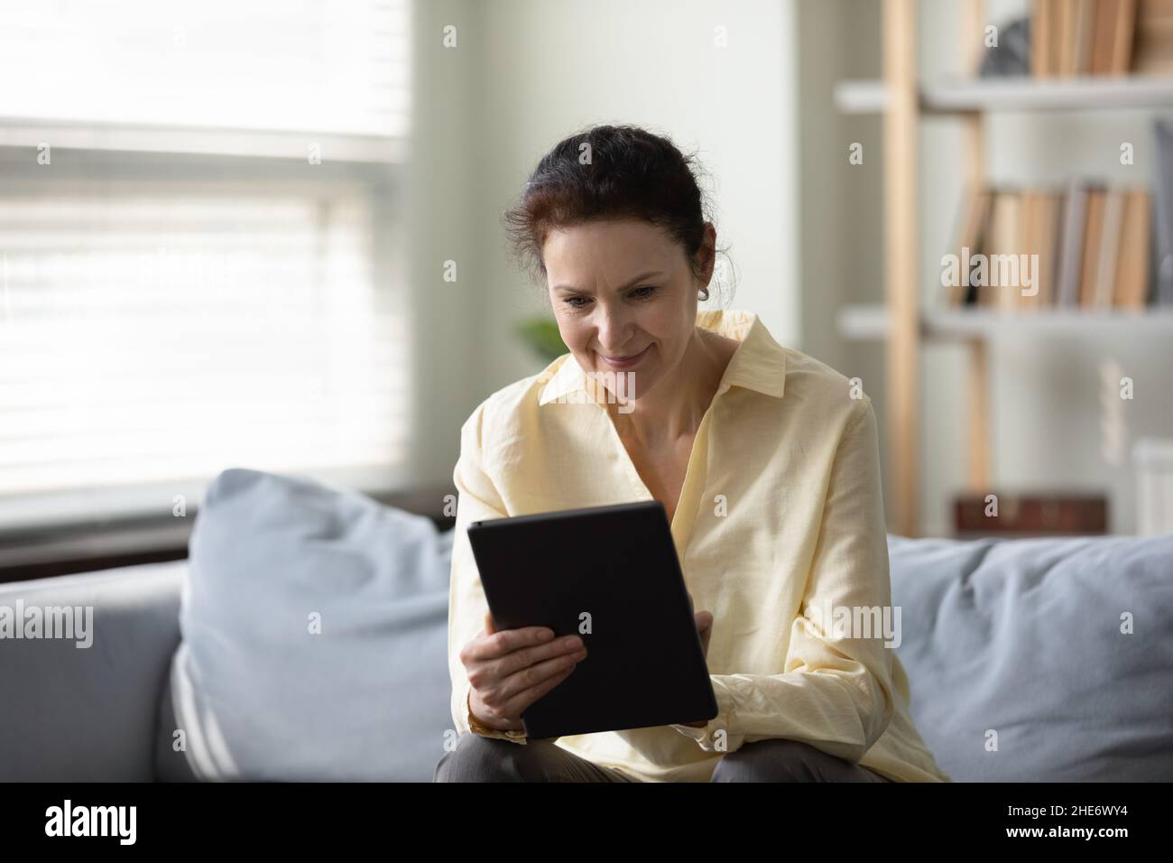 Happy old woman using digital tablet at home. Stock Photo