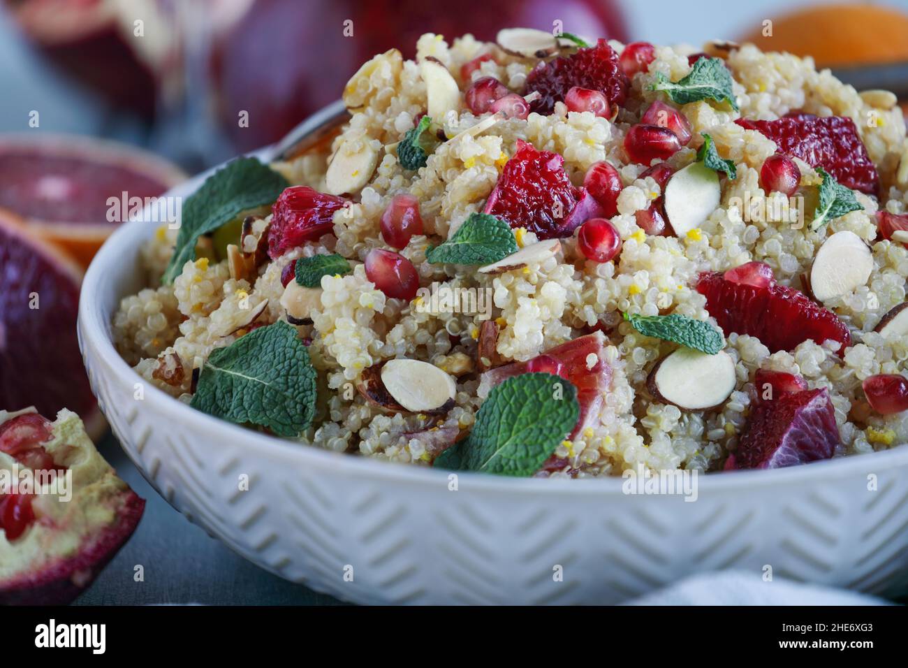A healthy lunch or dinner of a vegan / vegetarian Moroccan quinoa salad with mint, pomegranate and blood oranges. Selective focus with blurred foregro Stock Photo