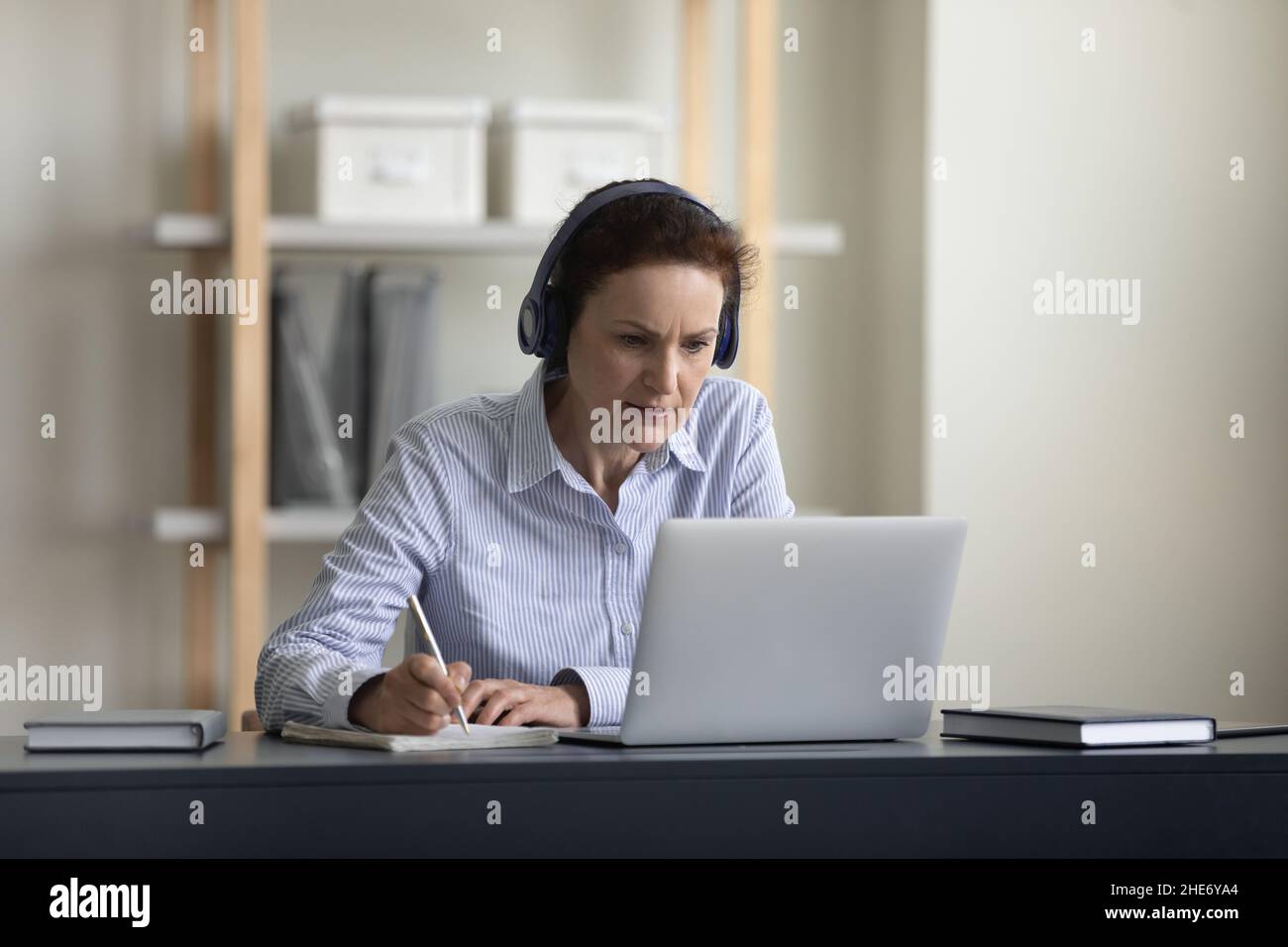 Happy middle aged woman e-learning at home. Stock Photo