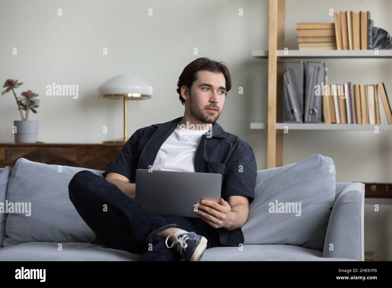 Happy carefree young man using computer at home. Stock Photo