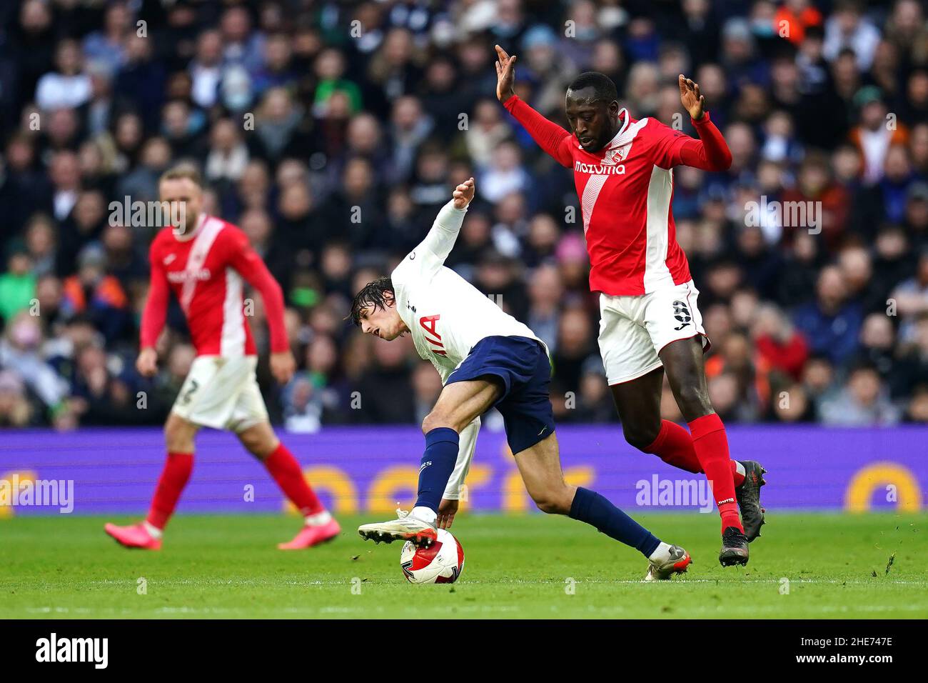 Tottenham Hotspur's Bryan Gil Salvatierra (centre) and Morcambe's Toumani Diagouraga (right) battle for the ball during the Emirates FA Cup third round match at Tottenham Hotspur Stadium, London. Picture date: Sunday January 9, 2022. Stock Photo