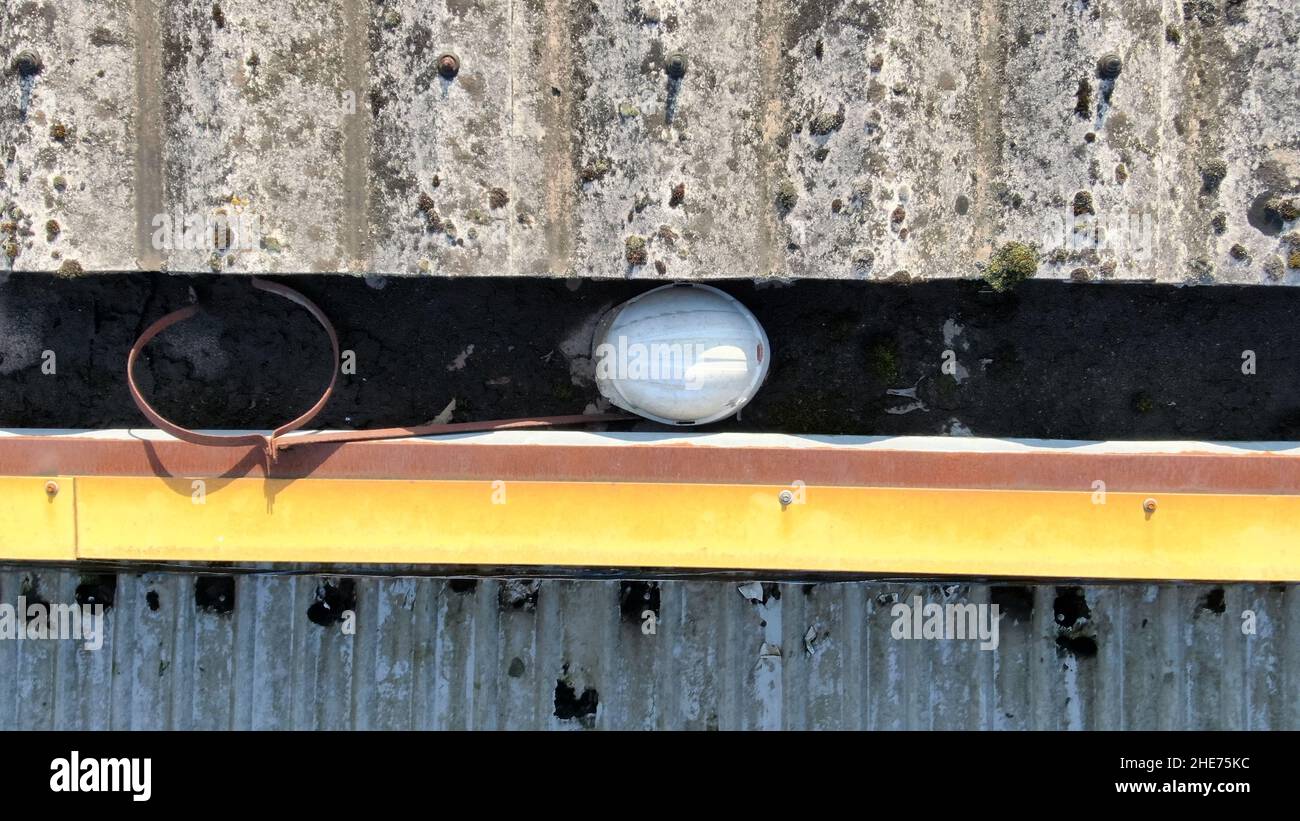 Aerial roof inspection of a metal roofed factory, showing objects stuck in the guttering. Stock Photo