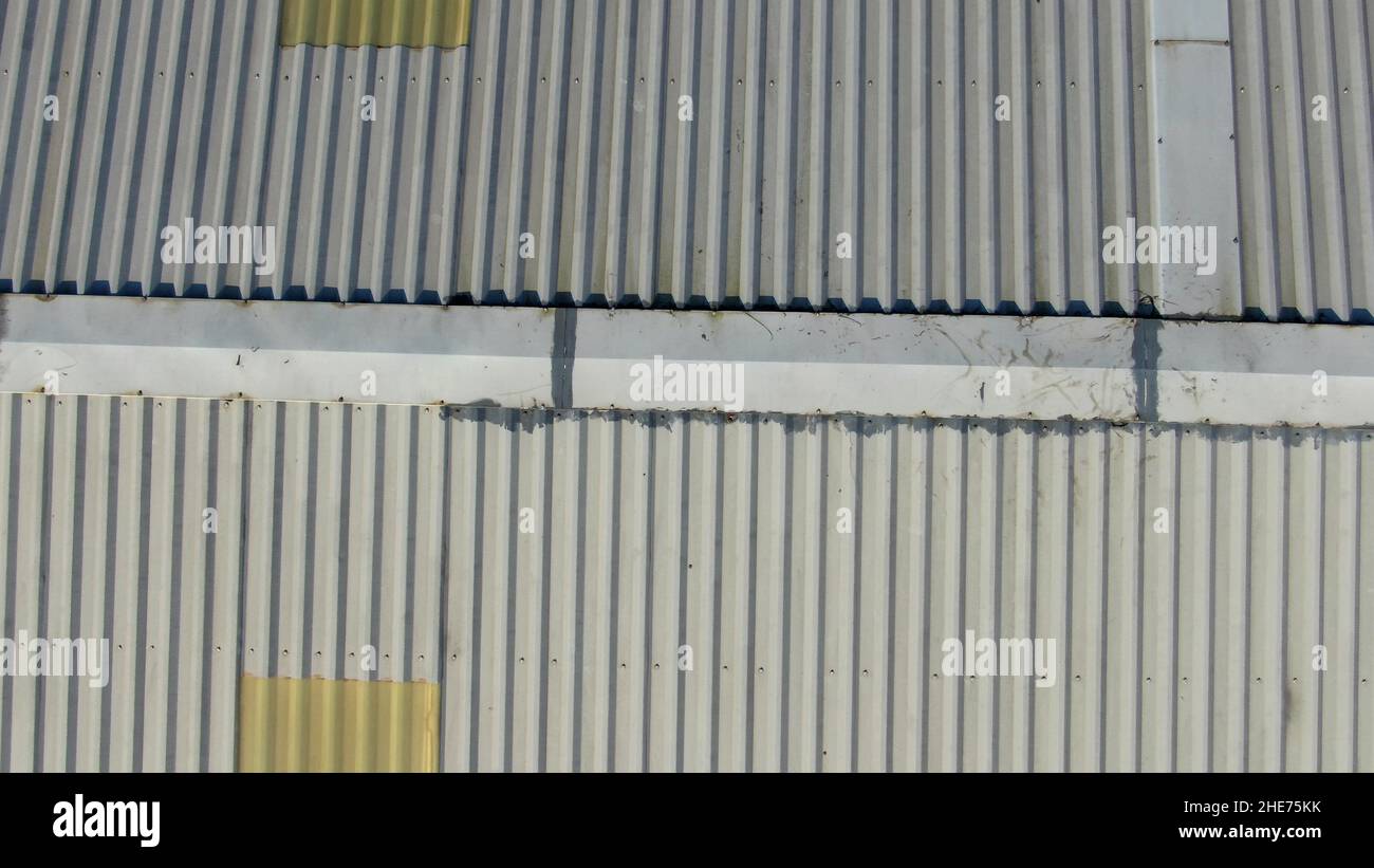 Aerial roof inspection of a metal roofed factory, showing the ridge with some repairs Stock Photo