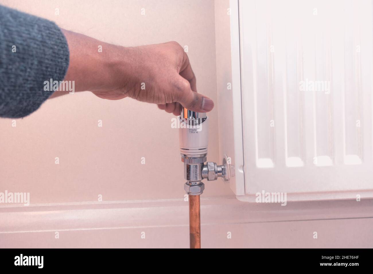 Central heating thermostat TRV adjustment by adult asian male to reduce or increase heat for increasing energy cost or colder weather concept Stock Photo