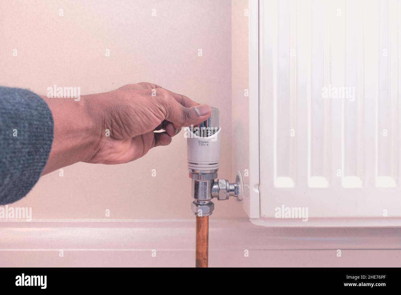 Central heating thermostat TRV adjustment by adult asian male to reduce or increase heat for increasing energy cost or colder weather concept Stock Photo