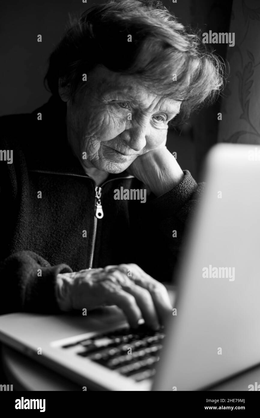 An senior woman working on the computer in her home. Black and white photo. Stock Photo