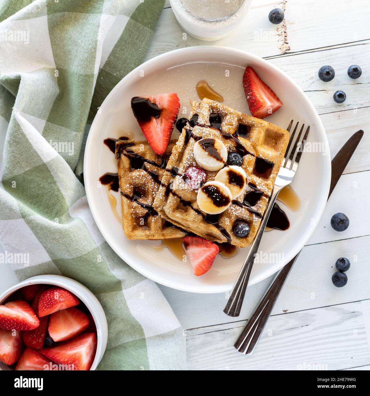 Top down view of waffles topped with fresh fruit, chocolate sauce and ...