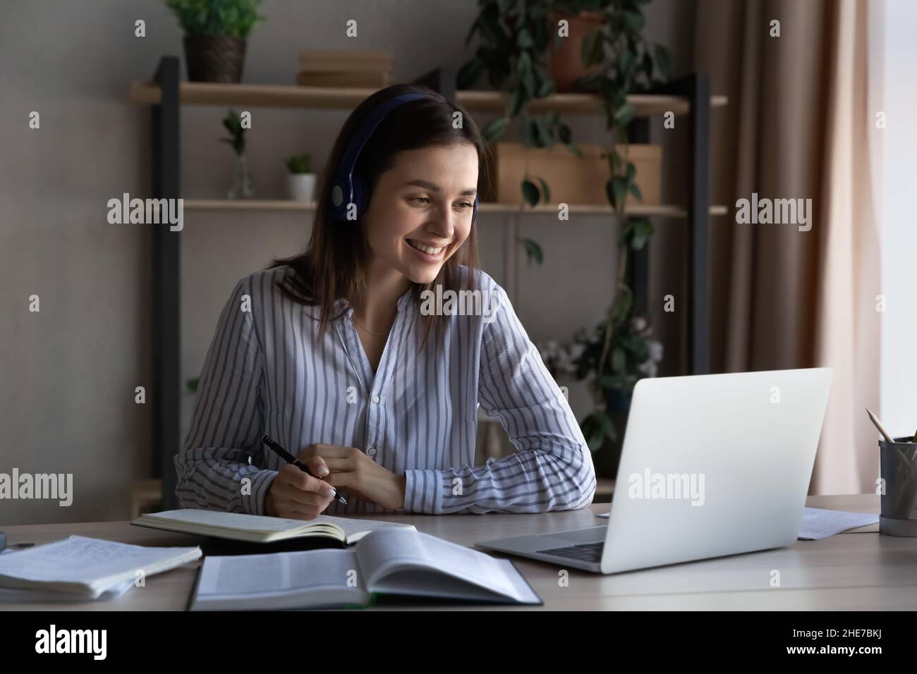 Happy millennial student girl in headphones studying from home Stock Photo