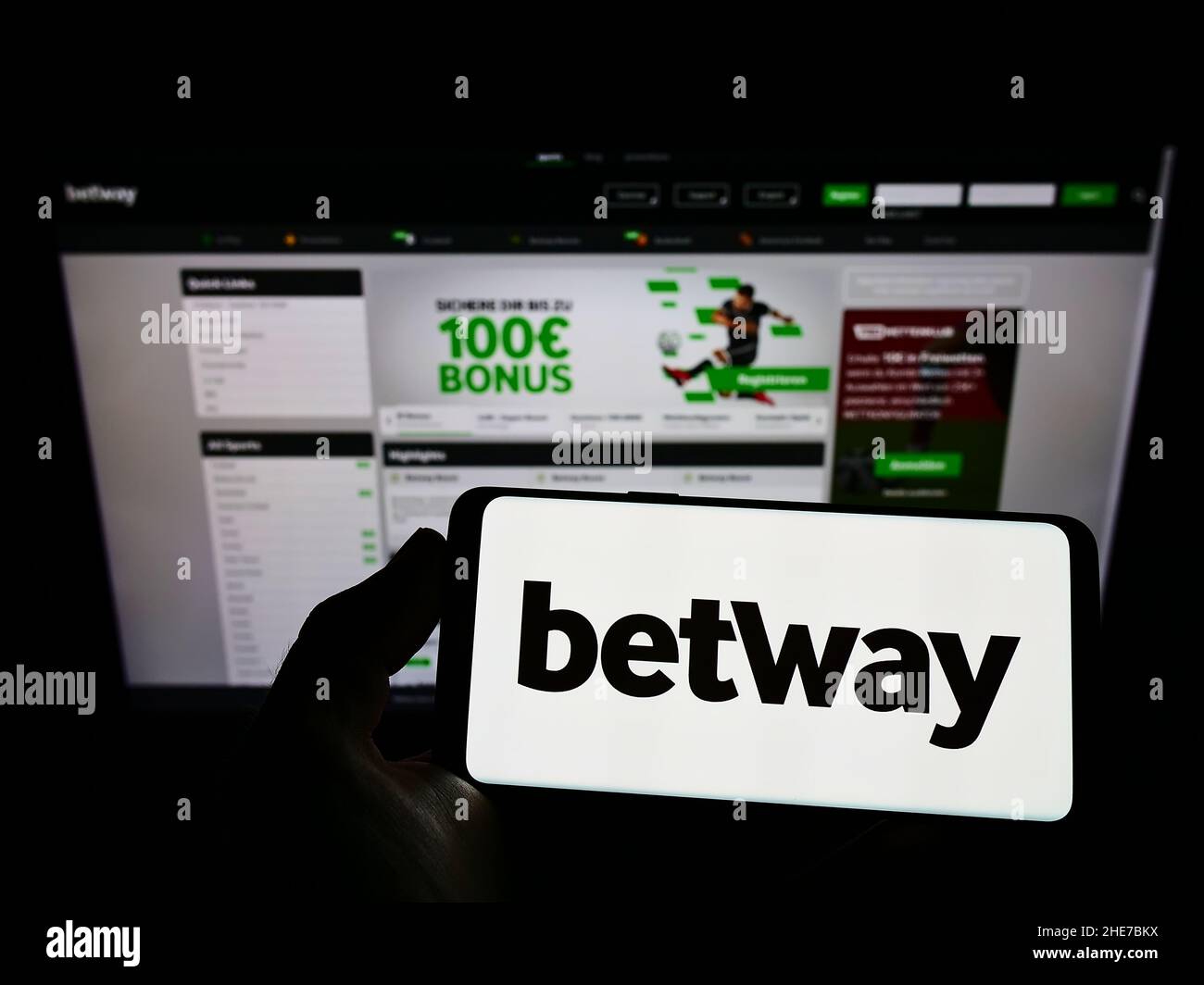 Person holding cellphone with logo of sports betting company Betway Group on screen in front of business webpage. Focus on phone display. Stock Photo