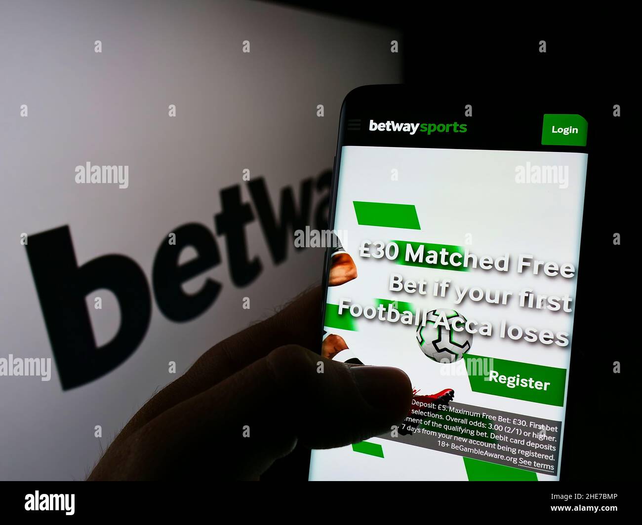 Person holding cellphone with webpage of sports betting company Betway Group on screen in front of logo. Focus on center of phone display. Stock Photo