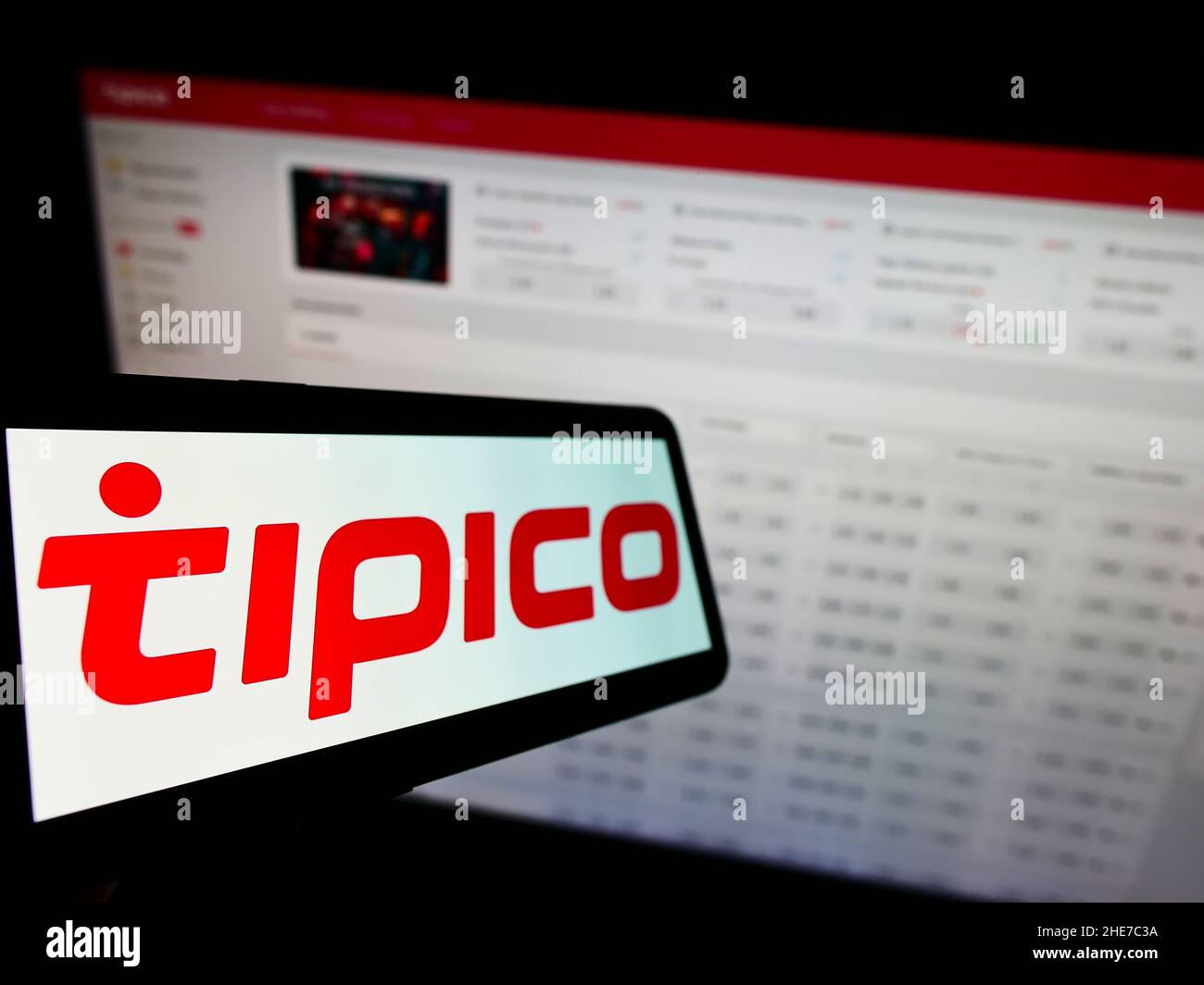 Cellphone with logo of sports betting company Tipico Co. Ltd on screen in front of business webpage. Focus on left of phone display. Stock Photo