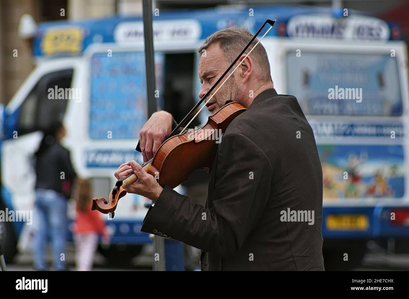 Man playing violin in the outdoor town centre market Stock Photo