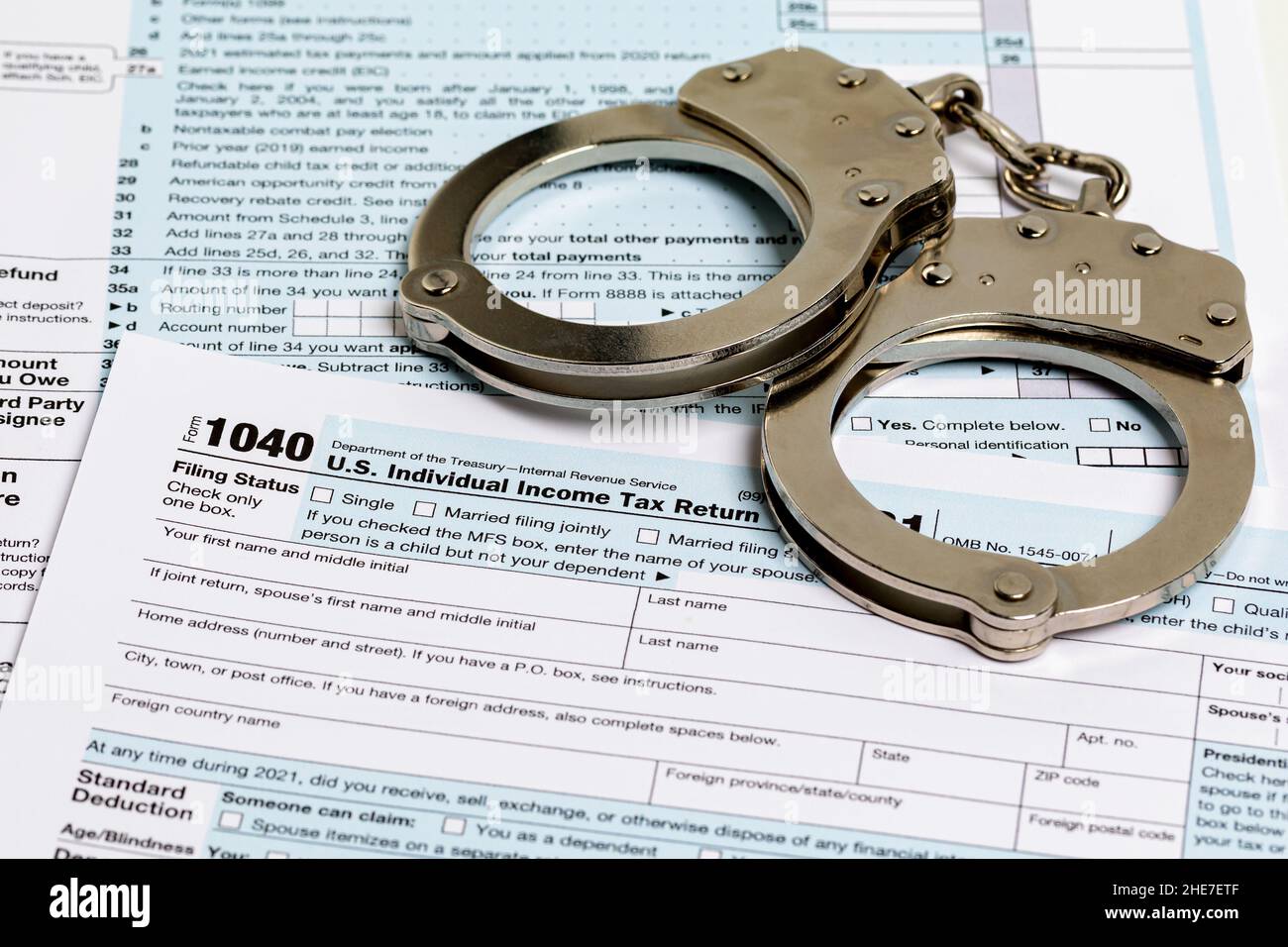 Income tax return documents and handcuffs. Tax evasion, crime and fraud concept. Stock Photo