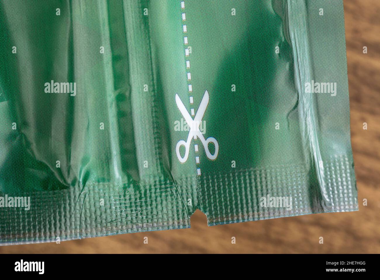 Macro shot of white scissors symbol and dotted cutting line on the plastic food packaging. For cutting along the line, cut above the rest metaphor. Stock Photo