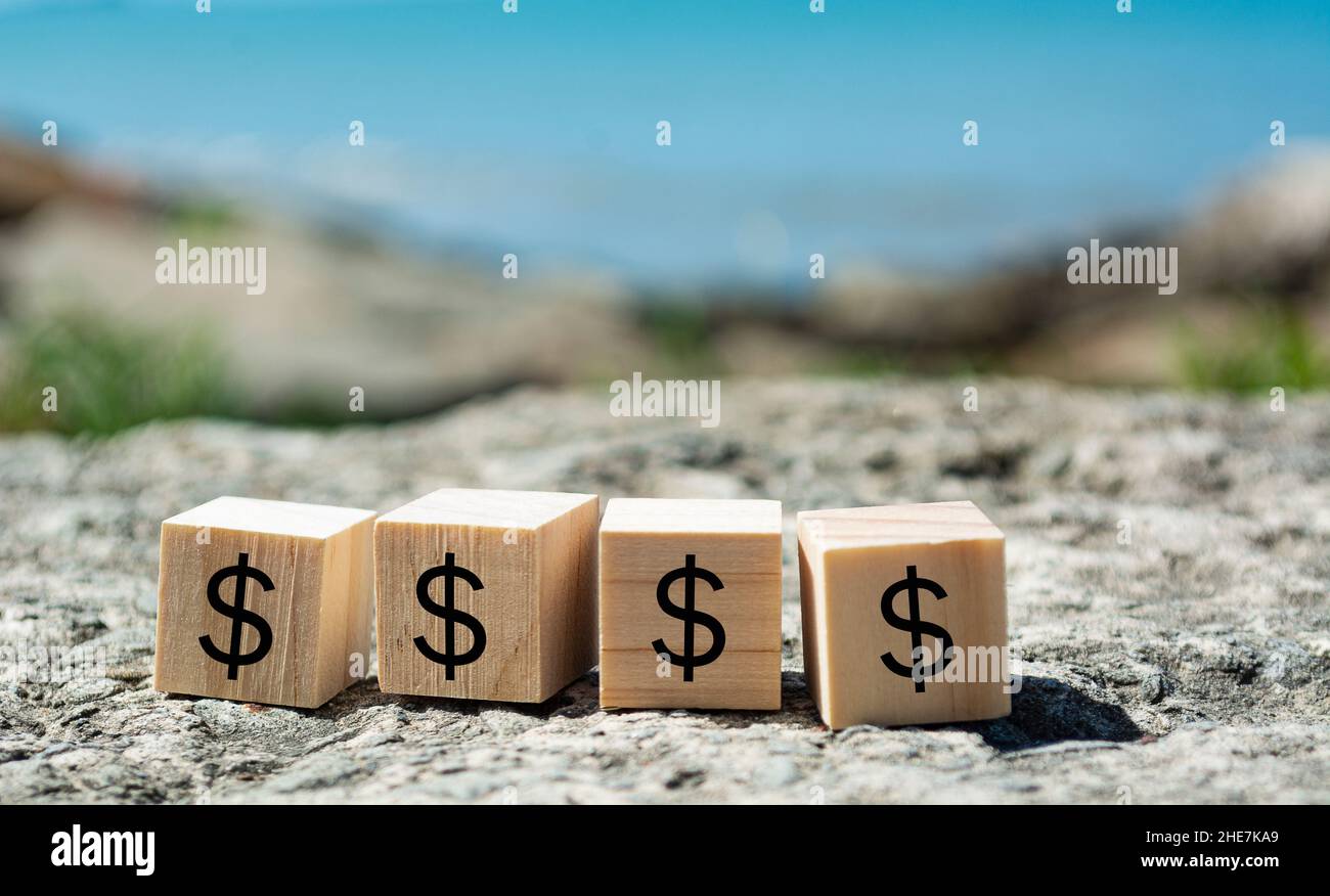 Dollar sign on wooden block with blurred background of blue ocean Stock Photo