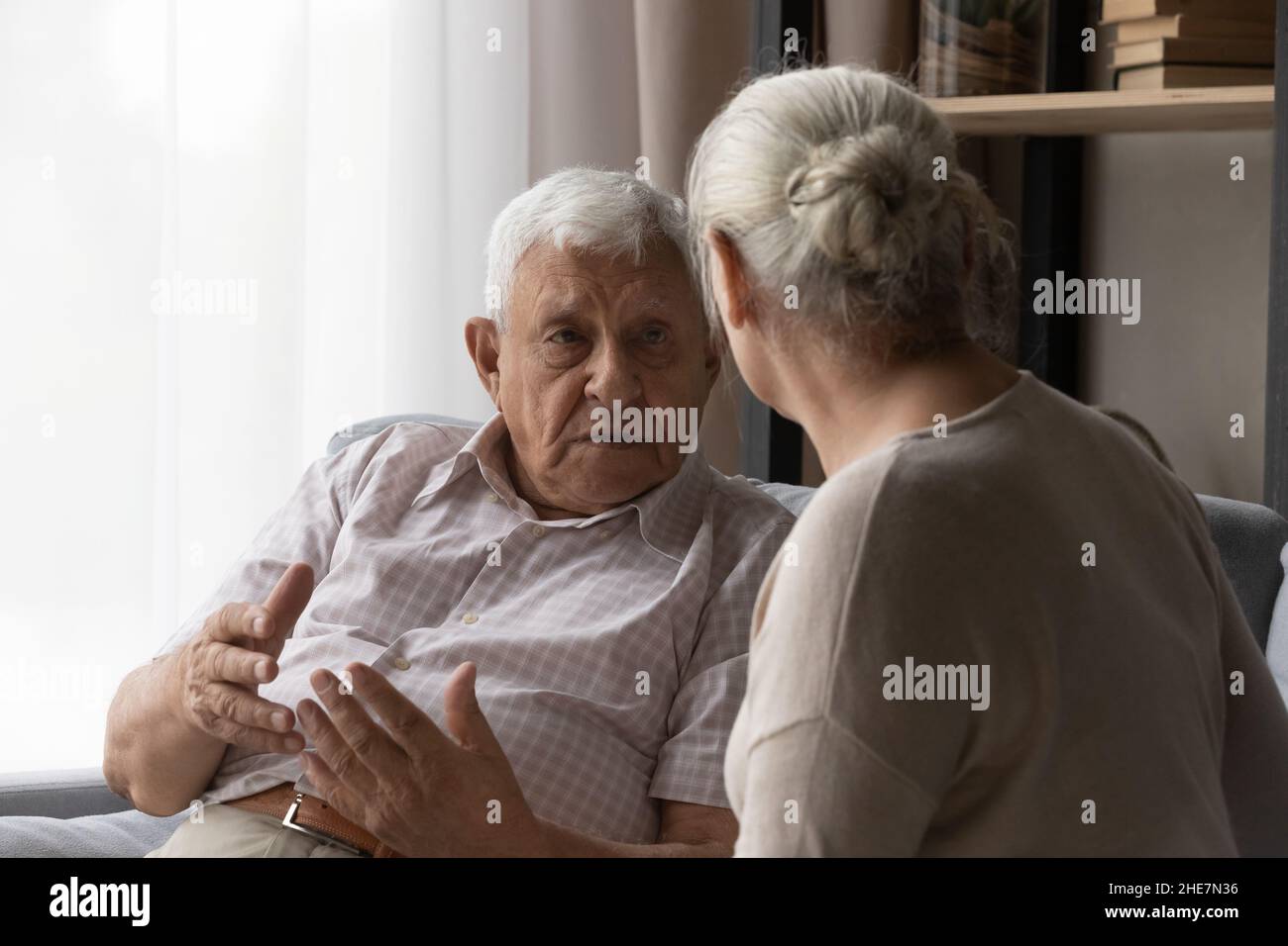 Stressed old man sharing problems with compassionate elderly wife. Stock Photo