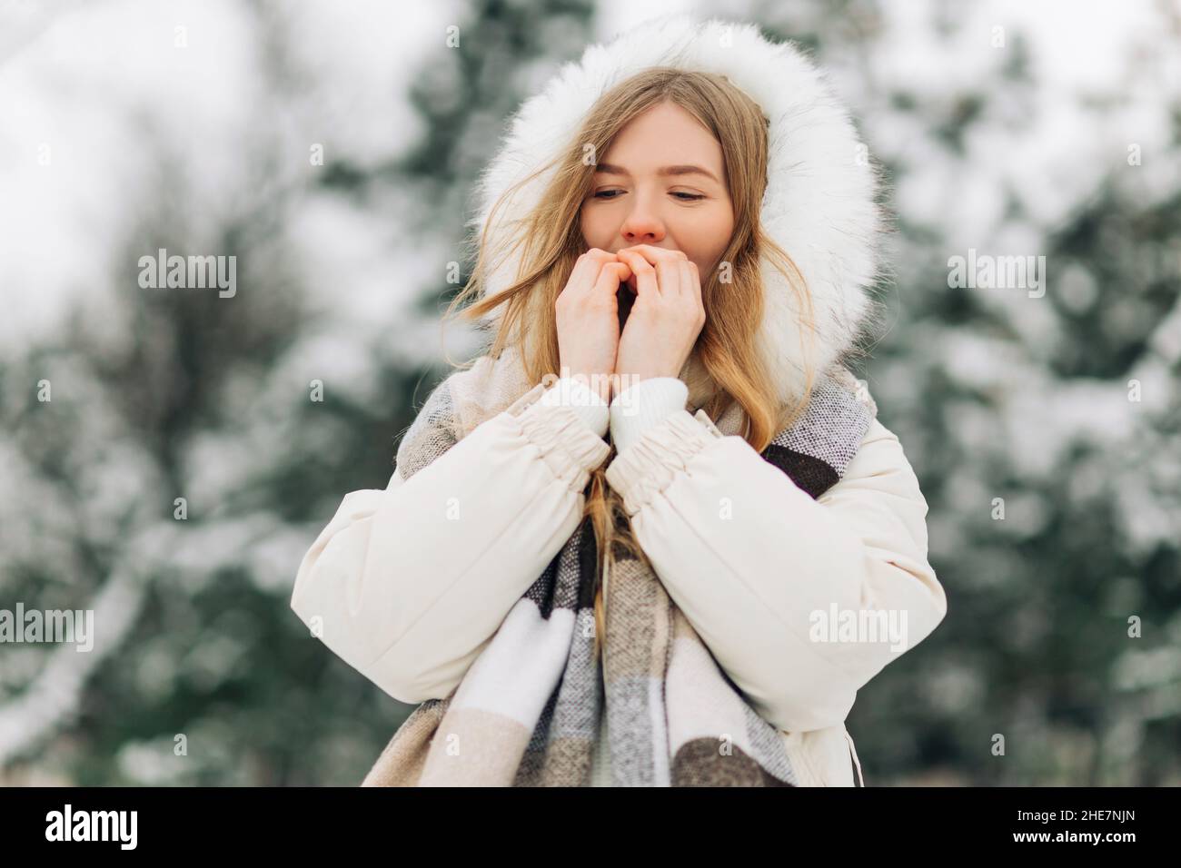 Happy girl warming up her hands in warm winter clothes. Attractive model  portrait outdoors on a cold day. Freezing a woman outside Stock Photo -  Alamy