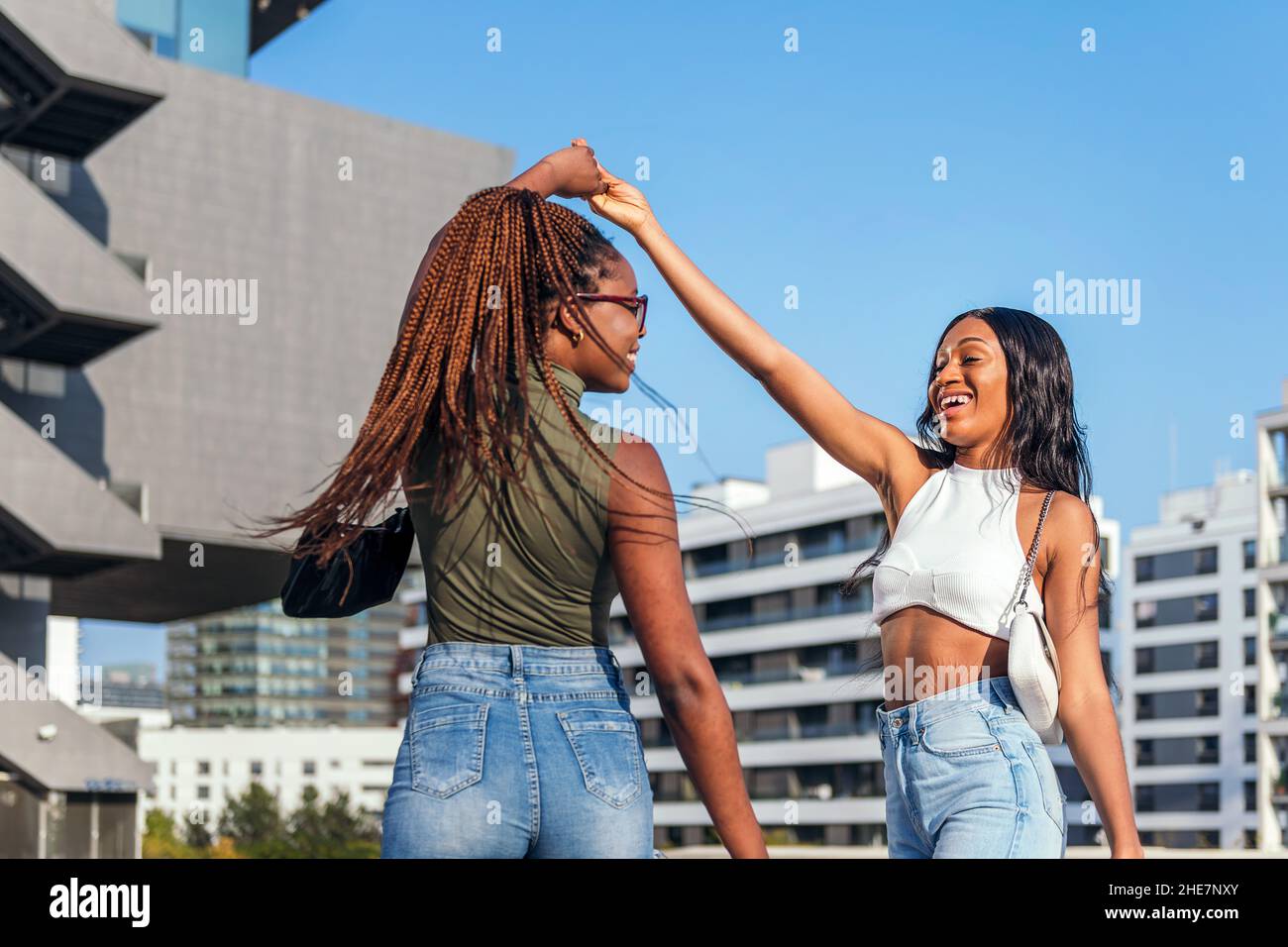 two young african friends dancing in the street holding hands, concept