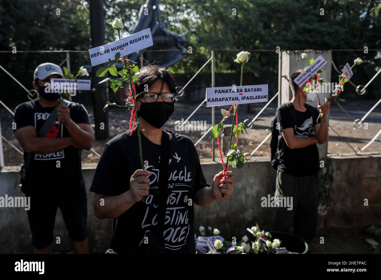 Human rights activists carry signs and offer flowers to remember fallen heroes in commemoration of the 73rd International Human Rights Day in Quezon City, Metro Manila. The monument honors the martyrs and heroes who struggled against the 21-year dictatorship of former President Ferdinand Marcos. Philippines. Stock Photo