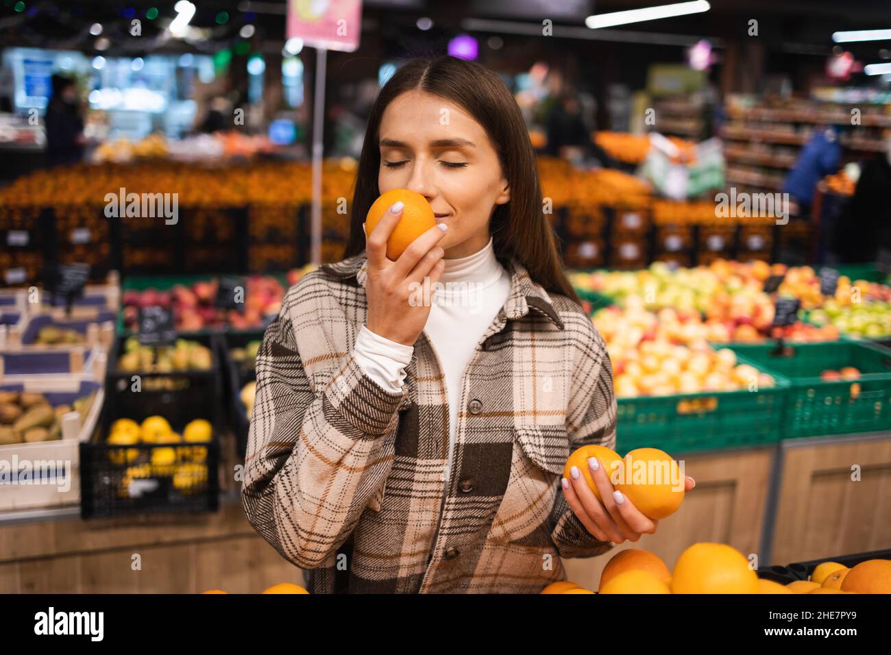 Portrait of a young woman picking oranges in a supermarket. Woman