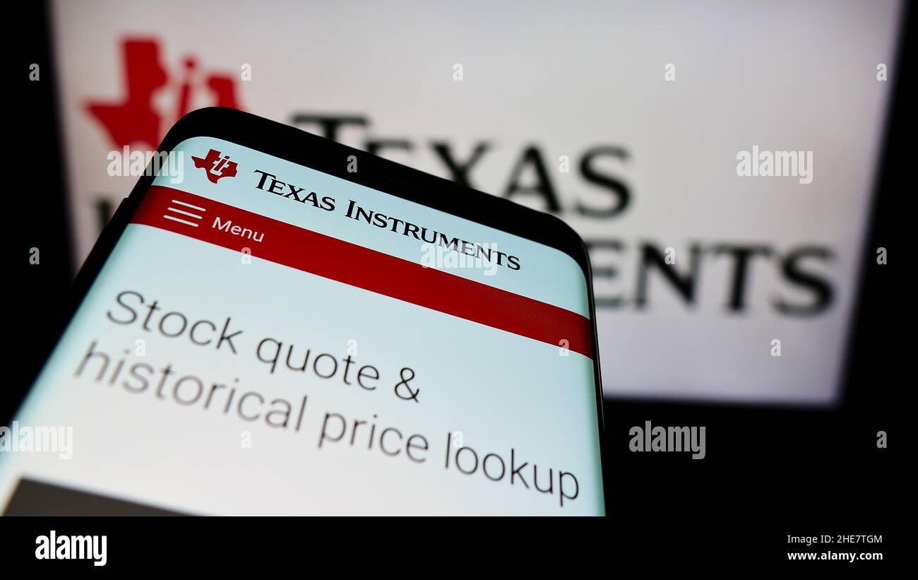 Smartphone with website of American company Texas Instruments Incorporated (TI) on screen in front of logo. Focus on top-left of phone display. Stock Photo