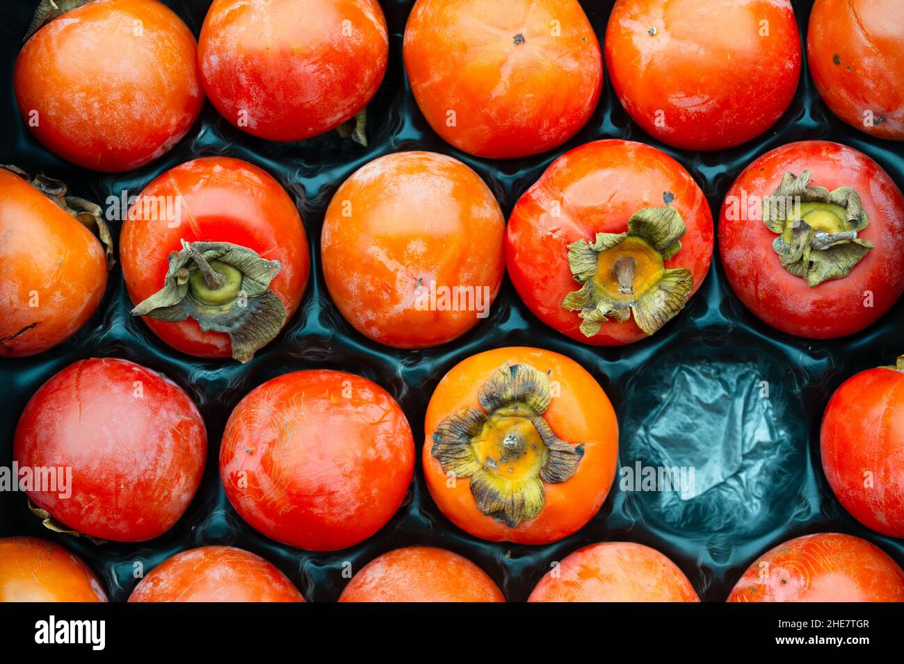 Directly above shot of persimmons in a fruit container Stock Photo