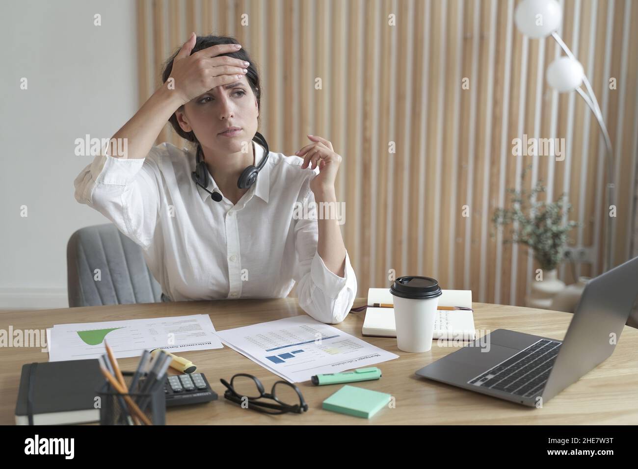 Overexhausted sick young italian woman office worker touching her forehead to check body temperature Stock Photo