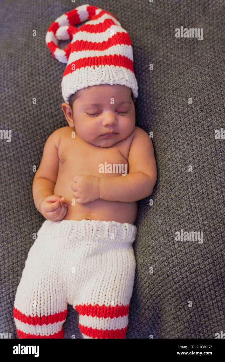 Lying newborn baby in a striped hat is asleep with his clenched fist