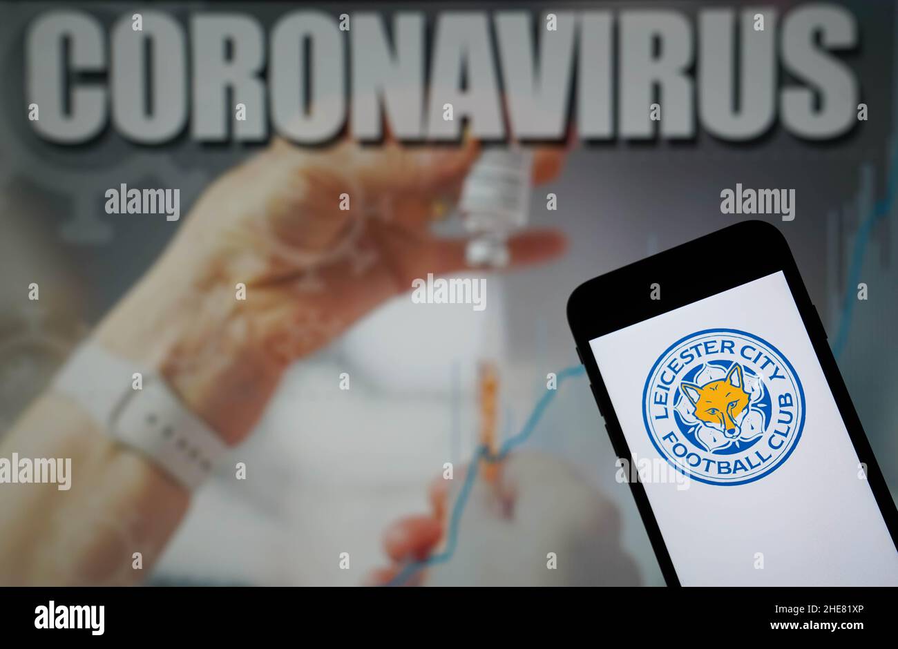 File photo dated 09-01-2021 of the Leicester City Football Club logo seen displayed on a mobile phone with a Coronavirus illustration on a monitor in the background. Leicester's trip to Everton on Tuesday has been postponed after the Foxes successfully applied to the Premier League to have the match rescheduled due to a lack of players. Despite fielding a side strong enough to beat Watford 4-1 in their FA Cup third-round tie on Saturday, Leicester said Covid cases, injuries and the Africa Cup of Nations had left them short. Issue date: Sunday January 9, 2021. Stock Photo