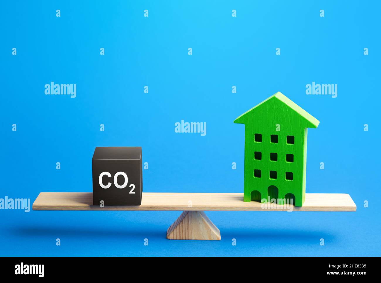 Residential building and CO2 emissions on scales. Greenhouse gas Emissions. Improving energy efficiency, lowering impact on environment. Decarbonizati Stock Photo