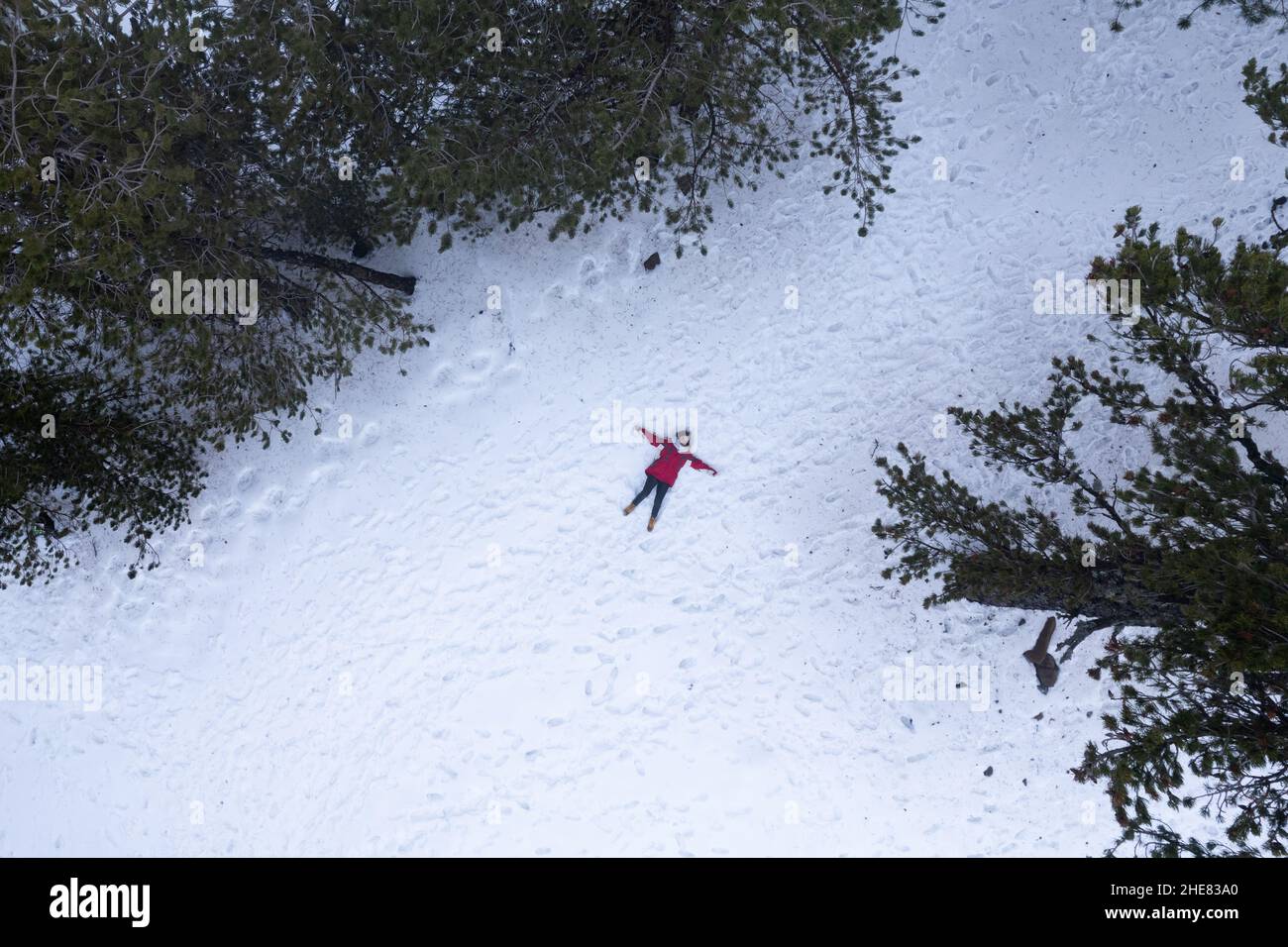 Drone aerial of woman wearing warm clothing lie down at snow in winter. Troodos cyprus Stock Photo