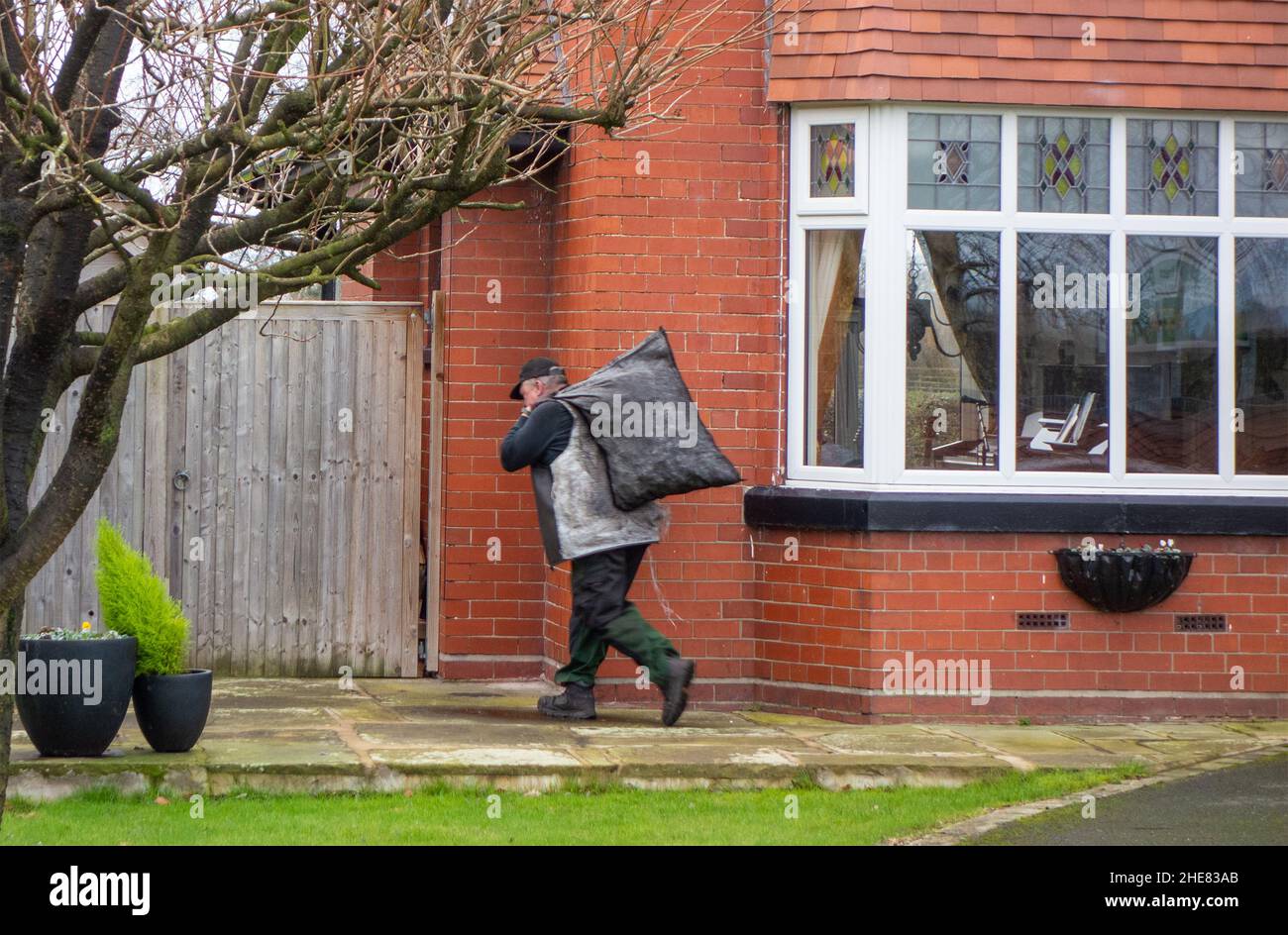 Coalman  coal man with sack of coal on his back delivering coal to a private house Stock Photo