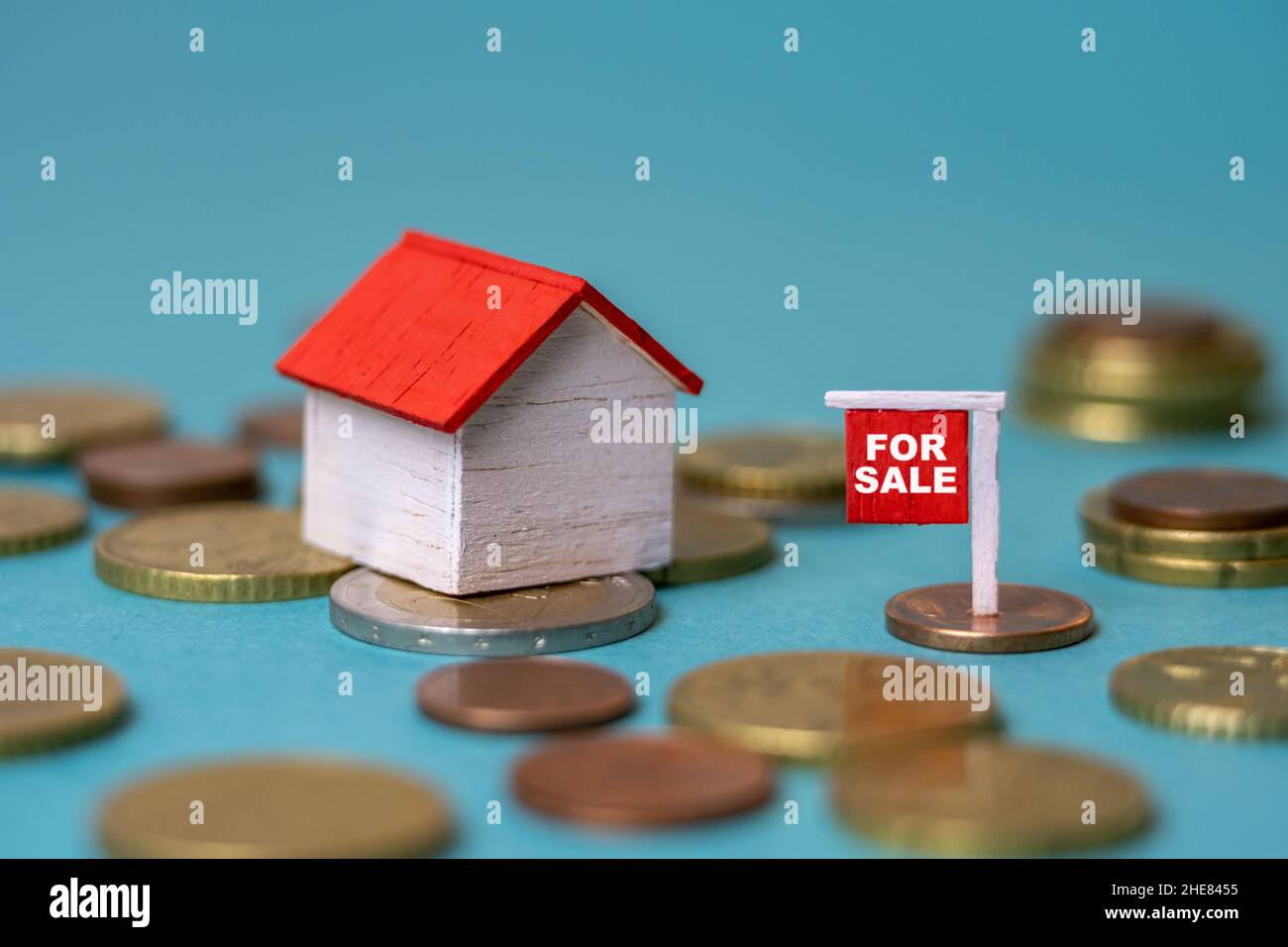 Tiny house on money and a for sale sign - Housing market, real estate, property investment, saving money, habitation cost concept Stock Photo