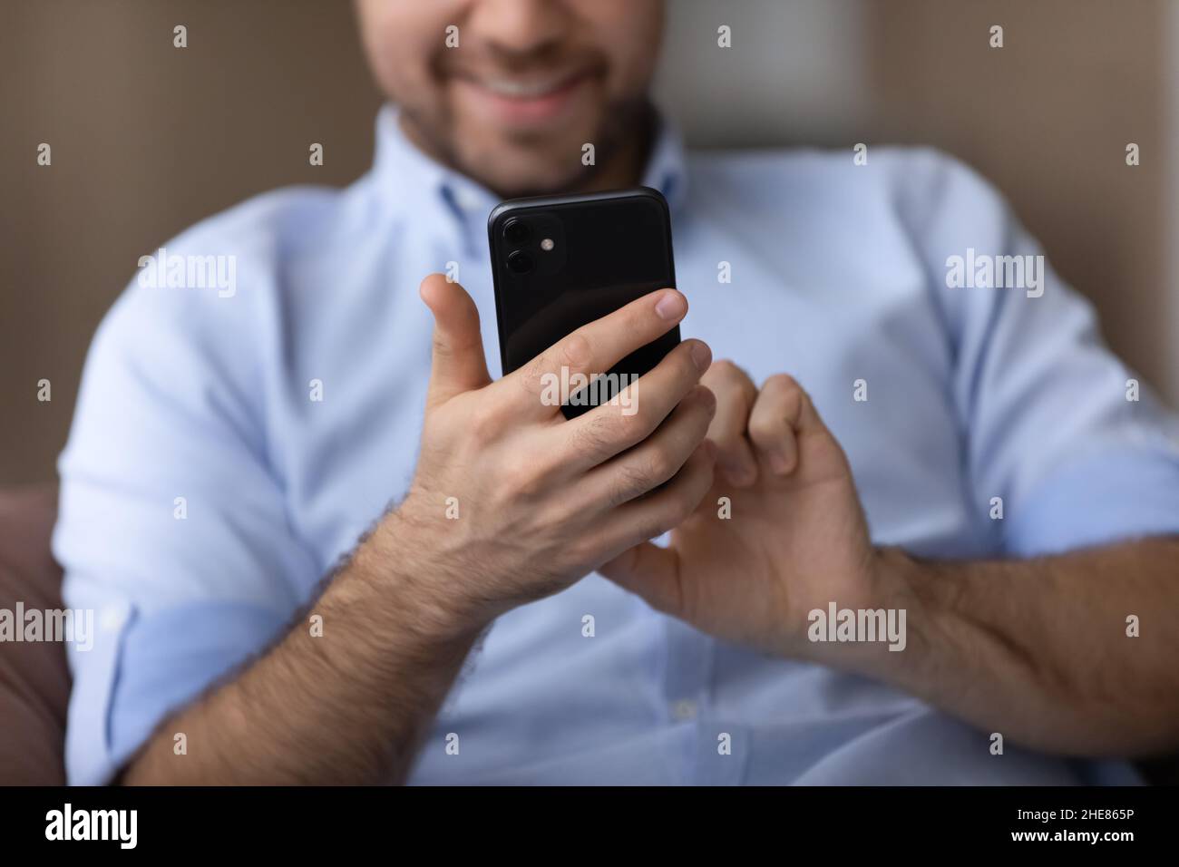Cropped close up smiling man using smartphone in hands Stock Photo