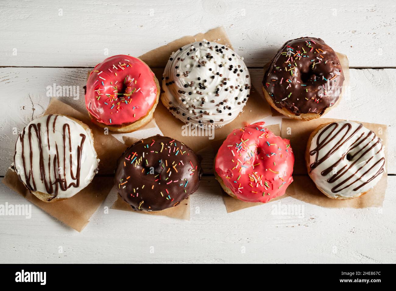 Delicious donuts with icing on a white wooden background. Stock Photo