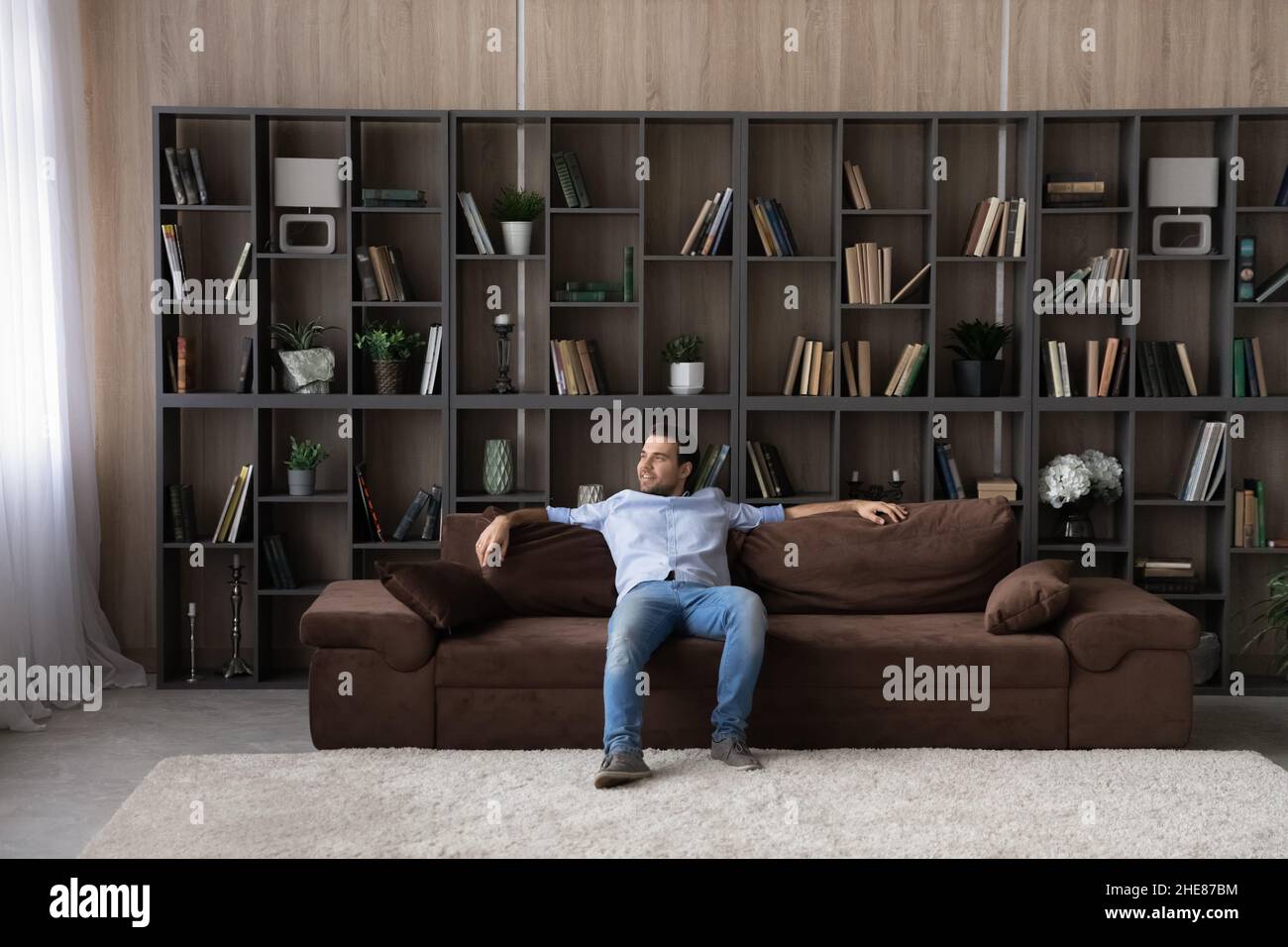 Full length relaxed man sitting on comfortable couch at home Stock Photo