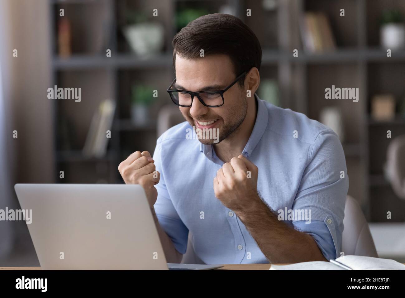 Head shot excited businessman in glasses celebrating success, using laptop Stock Photo