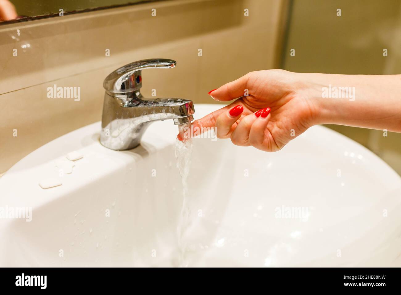 Woman taking a bath at home checking temperature touching running water